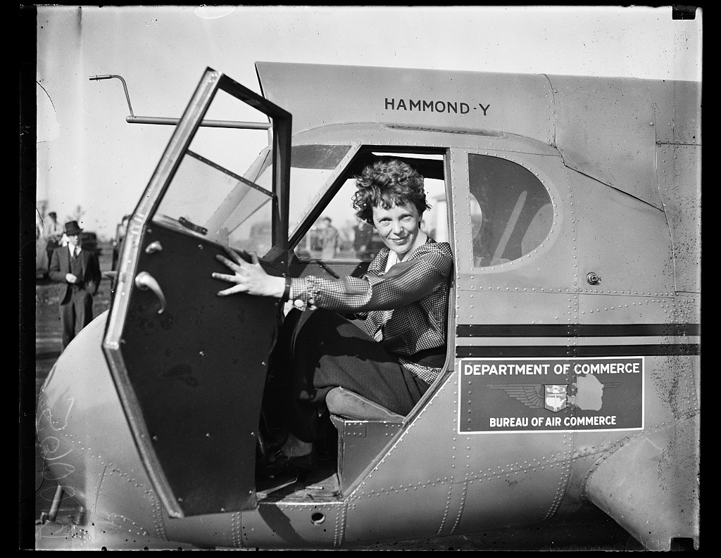 Earhart smiling from the doorway of an airplane