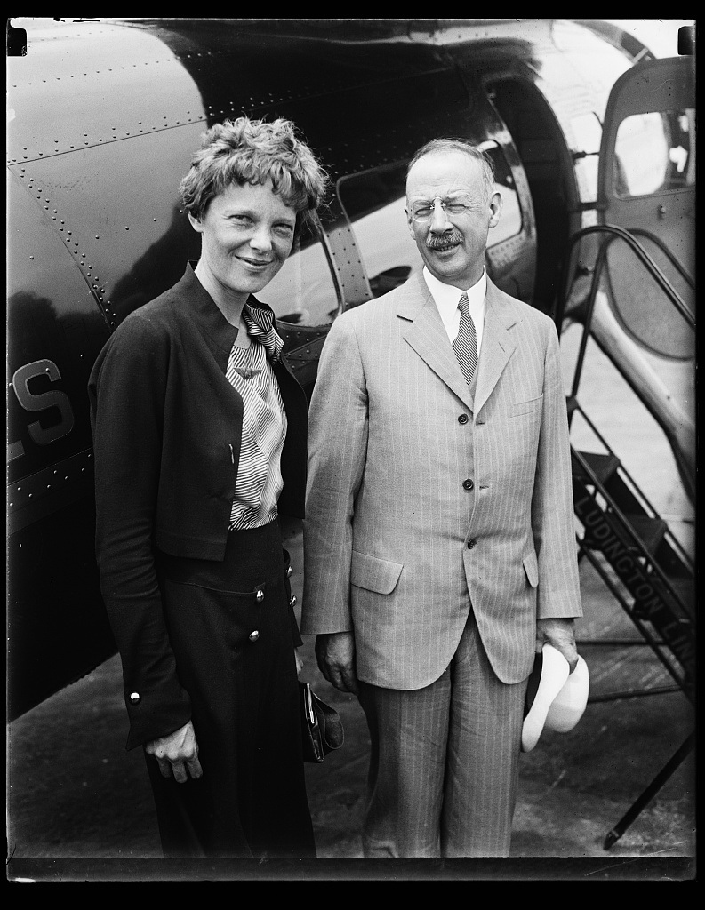 Amelia Earhart standing at left beside an airplane