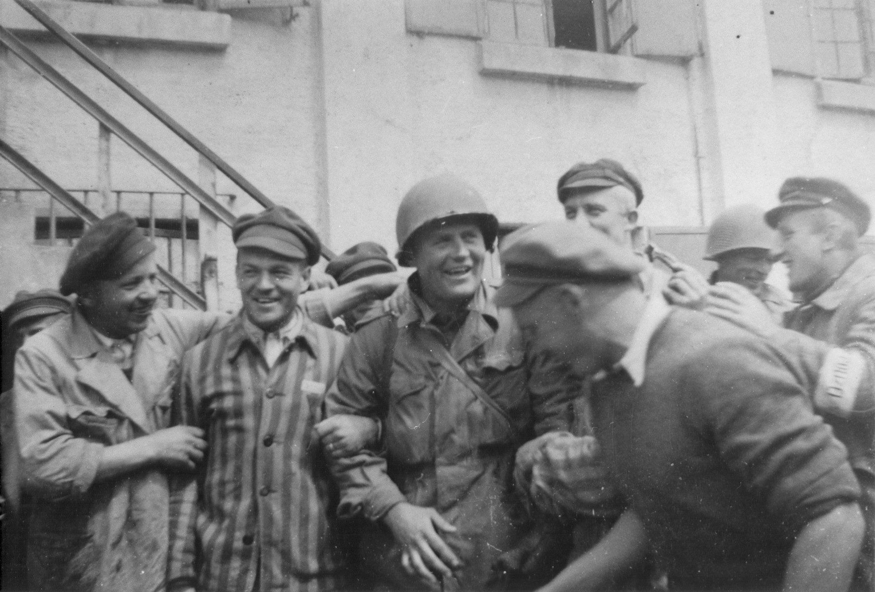 Survivors surround an American soldier following the liberation of Dachau on 29 April 1945.