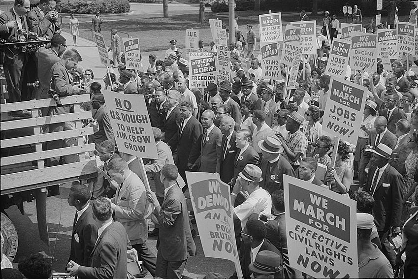 Civil rights leaders including Martin Luther King Jr. surrounded by marchers carrying signs in Washington in 1963