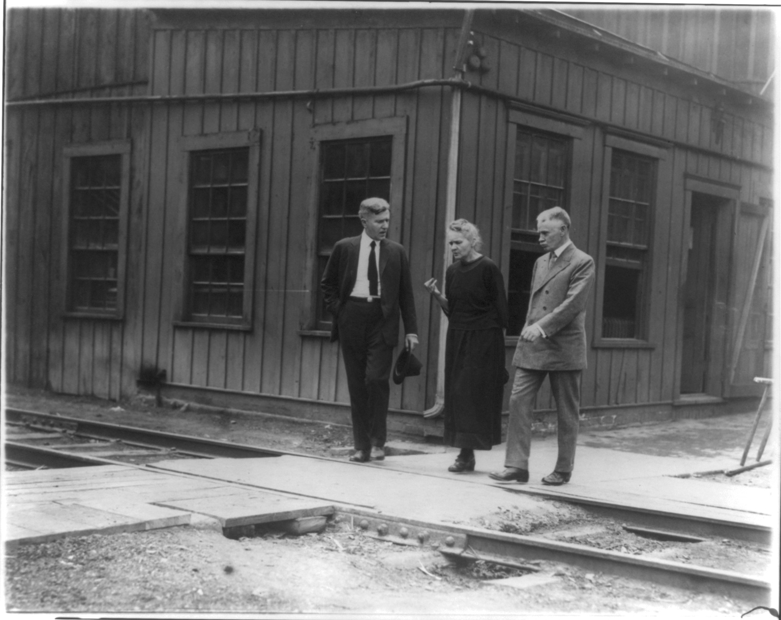 Marie Curie standing between two men during a 1921 visit