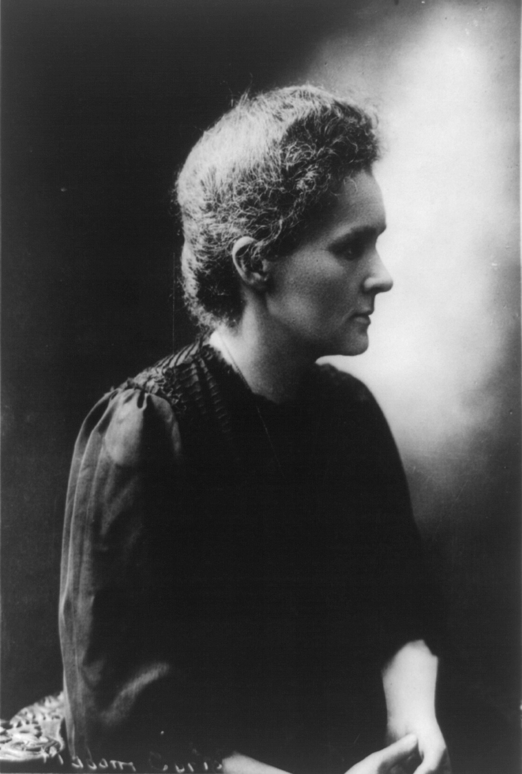 Seated Marie Curie shown in profile