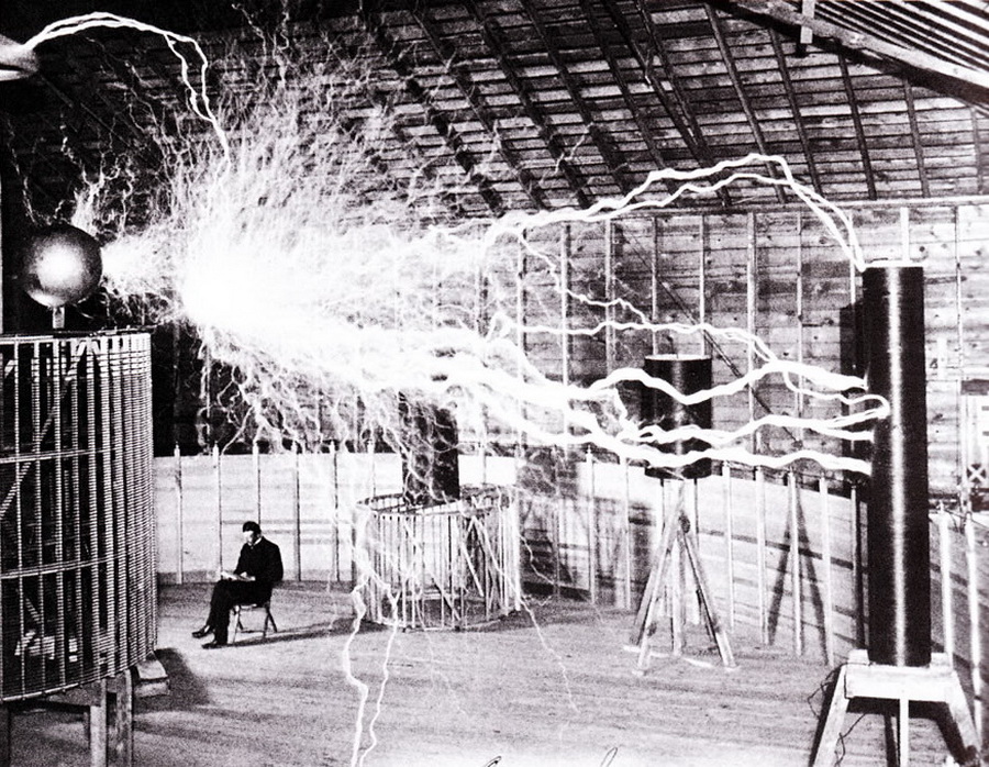 Double-exposure photograph of Tesla seated beside electrical discharges in his Colorado Springs laboratory