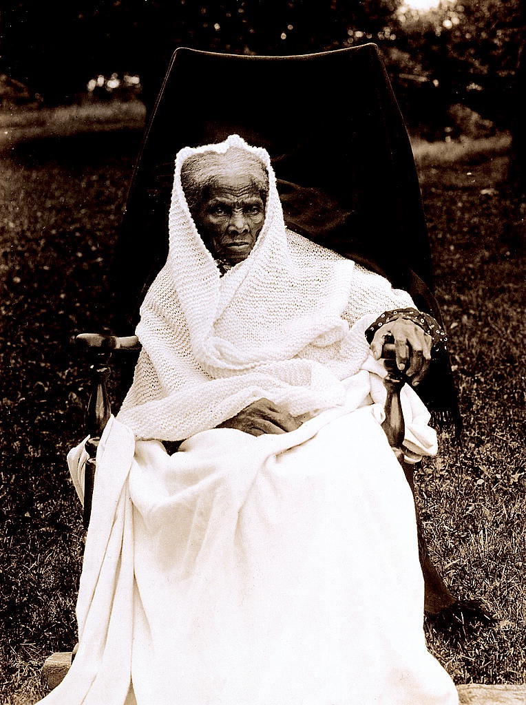 Elderly Harriet Tubman seated outdoors in white clothing