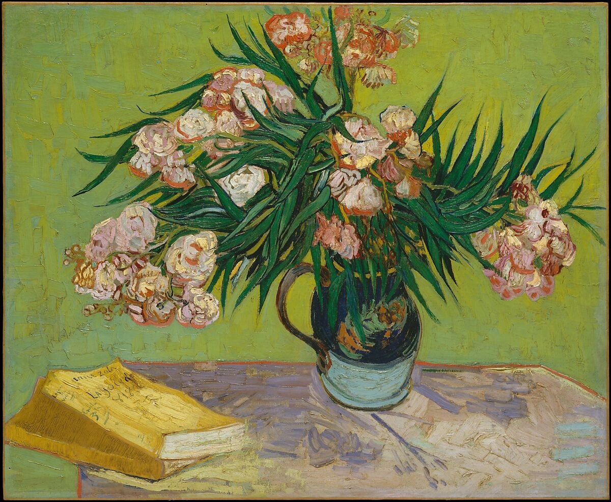 Pink oleander flowers in a vase beside books